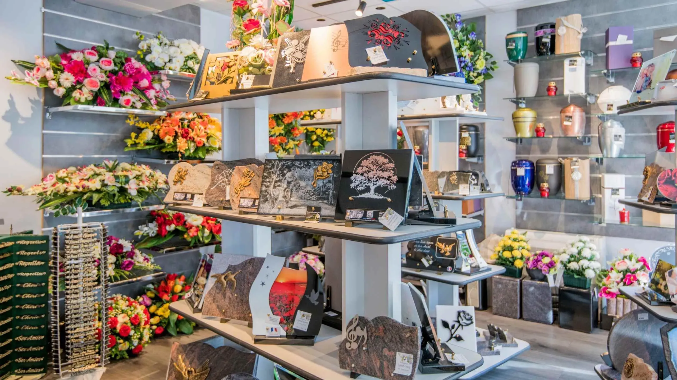 Exposition de plaques funéraires personnalisées, urnes et compositions florales en magasin.
