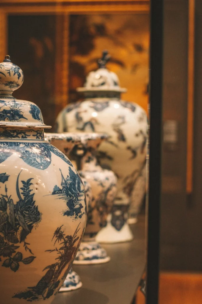 Urnes cinéraires en céramique décorées de motifs bleus exposées en vitrine.